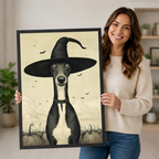 Woman holding a large framed Halloween canvas print of a greyhound wearing a witch hat, showing print size and black frame detail up close