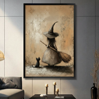 Black framed vintage witch and black cat canvas wall art with aged sandy textured background displayed in a modern dark gray living room with gray sofa, candlestick holders and tall black vase